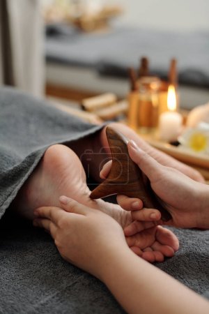 Téléchargez les photos : Pieds de femme obtenant réflexologie massage des pieds avec des bâtons en bois - en image libre de droit