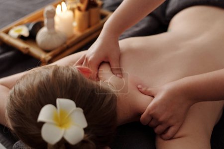 Téléchargez les photos : Mains de masseuse massant le cou et les épaules de la jeune femme - en image libre de droit