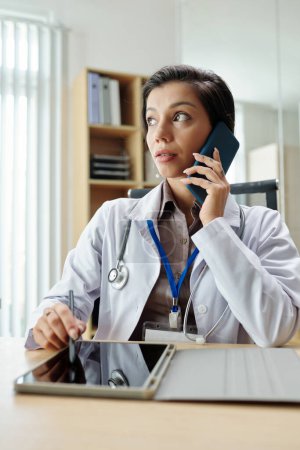 Téléchargez les photos : Médecin féminin parlant au téléphone avec le client - en image libre de droit