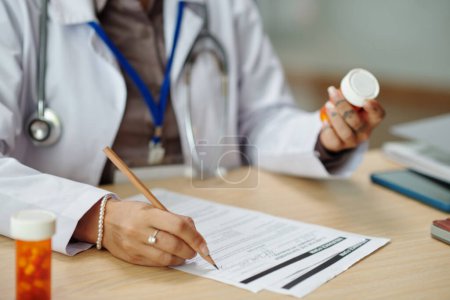 Photo for General practitioner writing out prescription for patient - Royalty Free Image