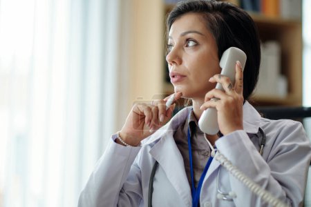 Téléchargez les photos : Portrait de femme médecin coûteuse répondant à l'appel téléphonique de la patiente et détournant les yeux - en image libre de droit