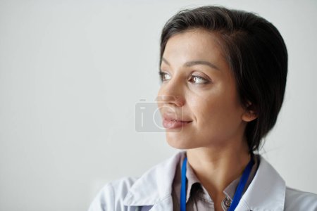 Téléchargez les photos : Portrait de femme médecin joyeux souriant et détournant les yeux - en image libre de droit