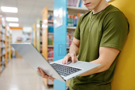 Photo for Serious young man working on laptop in college library - Royalty Free Image