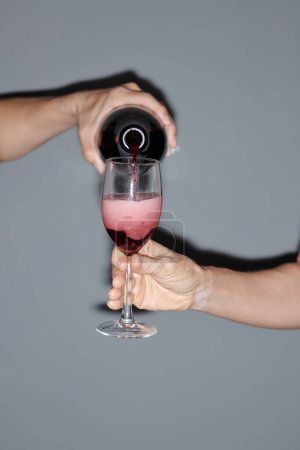 Photo for Man filling glass of party guest with red wine - Royalty Free Image