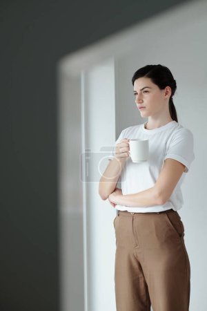 Foto de Retrato de una joven seria bebiendo café de la mañana y pensando en los planes para el día - Imagen libre de derechos