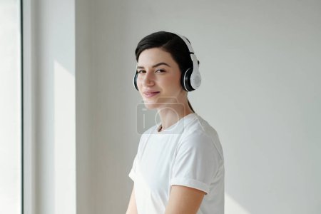 Photo for Portrait of smiling young woman listening to podcast or audiobook in headphone - Royalty Free Image