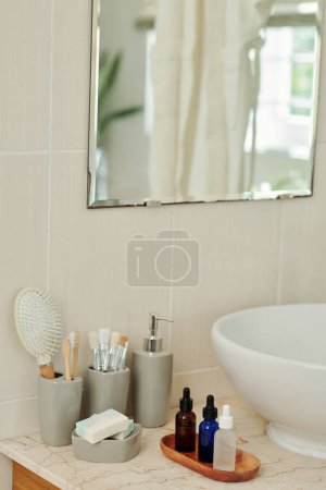 Photo for Vials with various serums and oils next to sink in bathroom - Royalty Free Image
