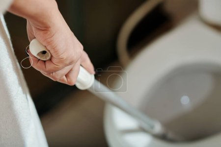 Foto de Imagen de primer plano de la mujer joven limpiando inodoro en apartamento - Imagen libre de derechos