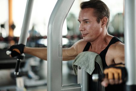 Téléchargez les photos : Homme en forme positif travaillant dans la salle de gym le matin - en image libre de droit