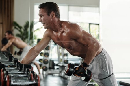 Photo for Shirtless strong middle-aged man working out in local gym oin the morning - Royalty Free Image