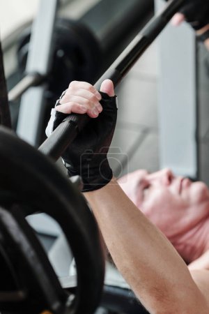 Téléchargez les photos : Déterminé homme mûr faisant banc presse exercice dans la salle de gym - en image libre de droit