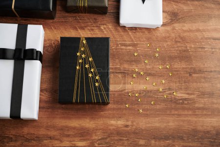 Téléchargez les photos : Cadeau d'anniversaire décoré sur la table à côté d'étoiles collantes étincelantes - en image libre de droit