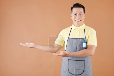 Photo for Portrait of smiling Asian hospitable waiter welcoming customers in coffeeshop or cafe - Royalty Free Image