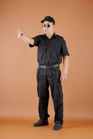 Photo for Serious security officer in cap and sunglasses pointing with index finger - Royalty Free Image