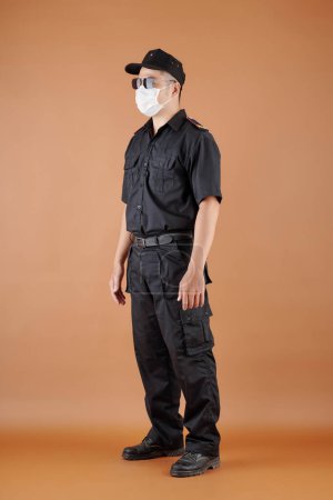 Photo for Full-length portrait of security guard in medical mask and sunglasses - Royalty Free Image