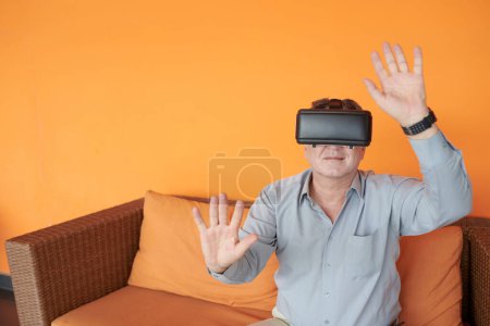 Foto de Empresario senior que usa auriculares de realidad virtual al explorar metaverse por primera vez - Imagen libre de derechos