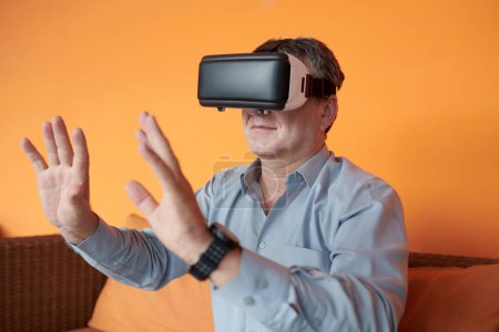 Téléchargez les photos : Homme d'affaires senior portant casque de réalité virtuelle lors de la communication avec d'autres avatars en métaverse - en image libre de droit