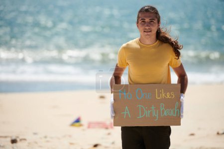 Photo for Positive young activist holding no one likes a dirty beach placard - Royalty Free Image