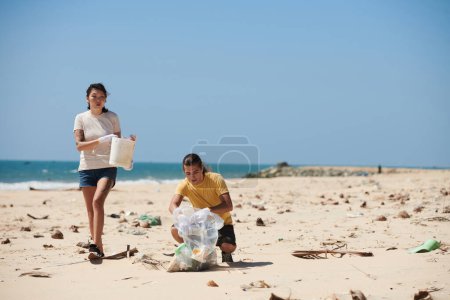 Photo for Team of volunteers picking up plastic bottles and other trash on beach to prevent garbage from flowing back into ocean - Royalty Free Image
