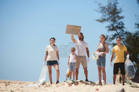 Foto de Grupo de voluntarios protestando y limpiando la playa sucia el día de la Tierra - Imagen libre de derechos