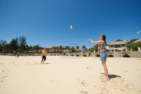Photo for Young couple ing volleyball on sandy beach on sunny day - Royalty Free Image
