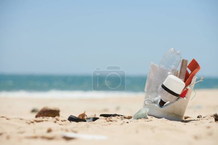Téléchargez les photos : Des déchets plastiques comme des bouteilles et des masques médicaux usagés sur une plage de sable fin. Concept de pollution marine - en image libre de droit