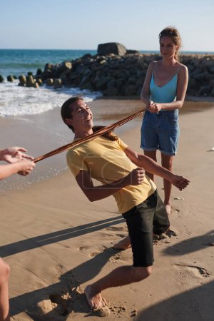Foto de Grupo de amigos alegres ing limbo juego en la playa, concepto de vacaciones de verano - Imagen libre de derechos