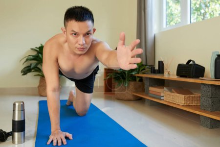 Photo for Determined fit young man practicing table top exercise on yoga mat at home - Royalty Free Image