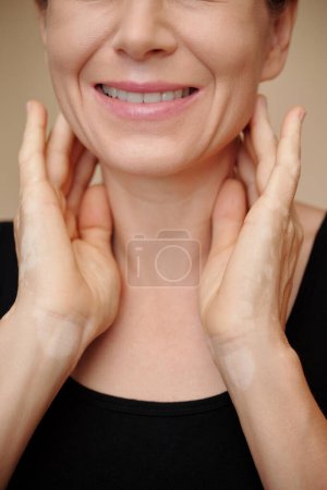 Foto de Imagen recortada de una mujer madura sonriente masajeando su cuello para reducir la hinchazón - Imagen libre de derechos