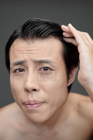 Foto de Hombre preocupante revisando su línea de cabello, concepto de pérdida de cabello - Imagen libre de derechos