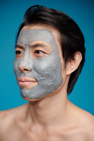 Photo for Happy man with exfoliating mask on his face looking away - Royalty Free Image
