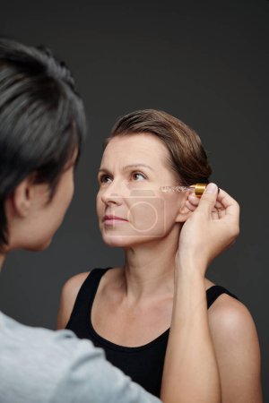 Photo for Man applying rejuvenating serum on face of mature woman - Royalty Free Image