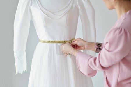 Photo for Seamstress measuring waist of mannequin with wedding dress - Royalty Free Image