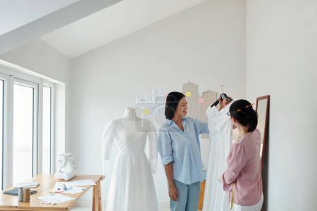 Photo for Tailor showing finished wedding dress to client - Royalty Free Image