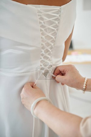 Photo for Mother helping daughter to tie up corset of wedding dress - Royalty Free Image