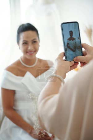 Photo for Mother photographing daughter in wedding dress - Royalty Free Image