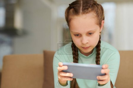 Photo for Girl watching short videos on smartphone after school - Royalty Free Image
