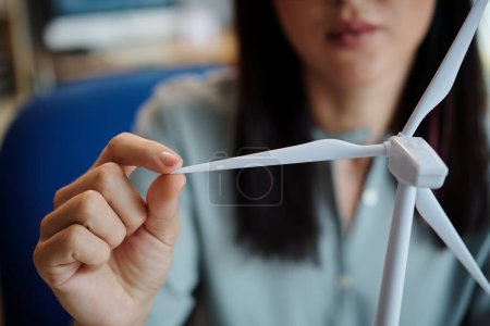 Photo for Closeup image of woman touching blate of small plastic wind turbine - Royalty Free Image