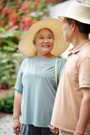 Téléchargez les photos : Heureuse femme âgée en chapeau de paille regardant son mari avec amour et tendresse - en image libre de droit