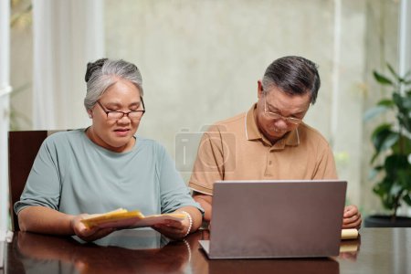 Téléchargez les photos : Couple aîné payer des factures en ligne, concept de comptabilité à la maison - en image libre de droit