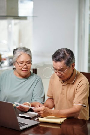 Photo for Senior couple figuring out how to pay taxes and bills online - Royalty Free Image