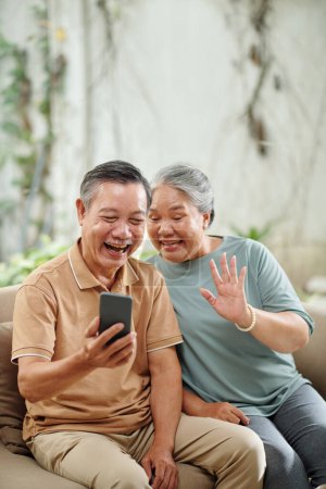 Téléchargez les photos : Joyeux couple âgé vidéo appelant leurs petits-enfants ou amis - en image libre de droit