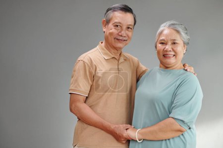 Photo for Portrait of smiling elderly couple holding hands and looking at camera - Royalty Free Image