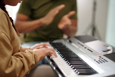 Foto de Profesor orgulloso aplaudiendo a estudiante tocando melodía en piano electrónico - Imagen libre de derechos