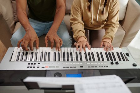 Photo for Hands of student and teacher playing synthesizer together, view from above - Royalty Free Image