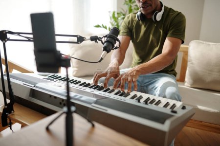 Téléchargez les photos : Musicien s'enregistrant en jouant du piano électronique et en chantant - en image libre de droit