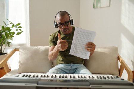 Photo for Music teacher holding music notes and showing thumbs-up - Royalty Free Image