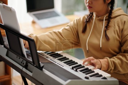 Photo for Cropped image of teenage girl playing synthesizer at home - Royalty Free Image