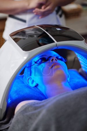 Photo for Woman getting blue light skin treatment in beauty salon - Royalty Free Image