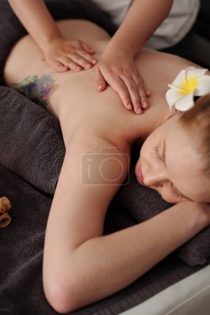 Téléchargez les photos : Masseuse massage dos de jeune femme dans le salon de beauté - en image libre de droit